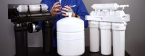 A person in a blue uniform shirt handling water filtration equipment
